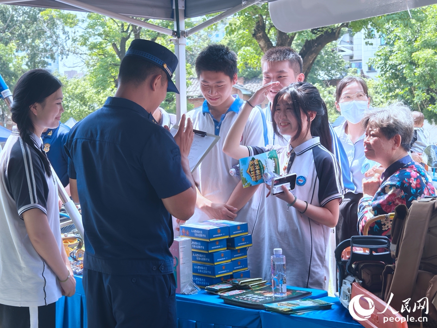 消防员为学生们发放防灾减灾宣传手册。人民网 杨灏昱摄